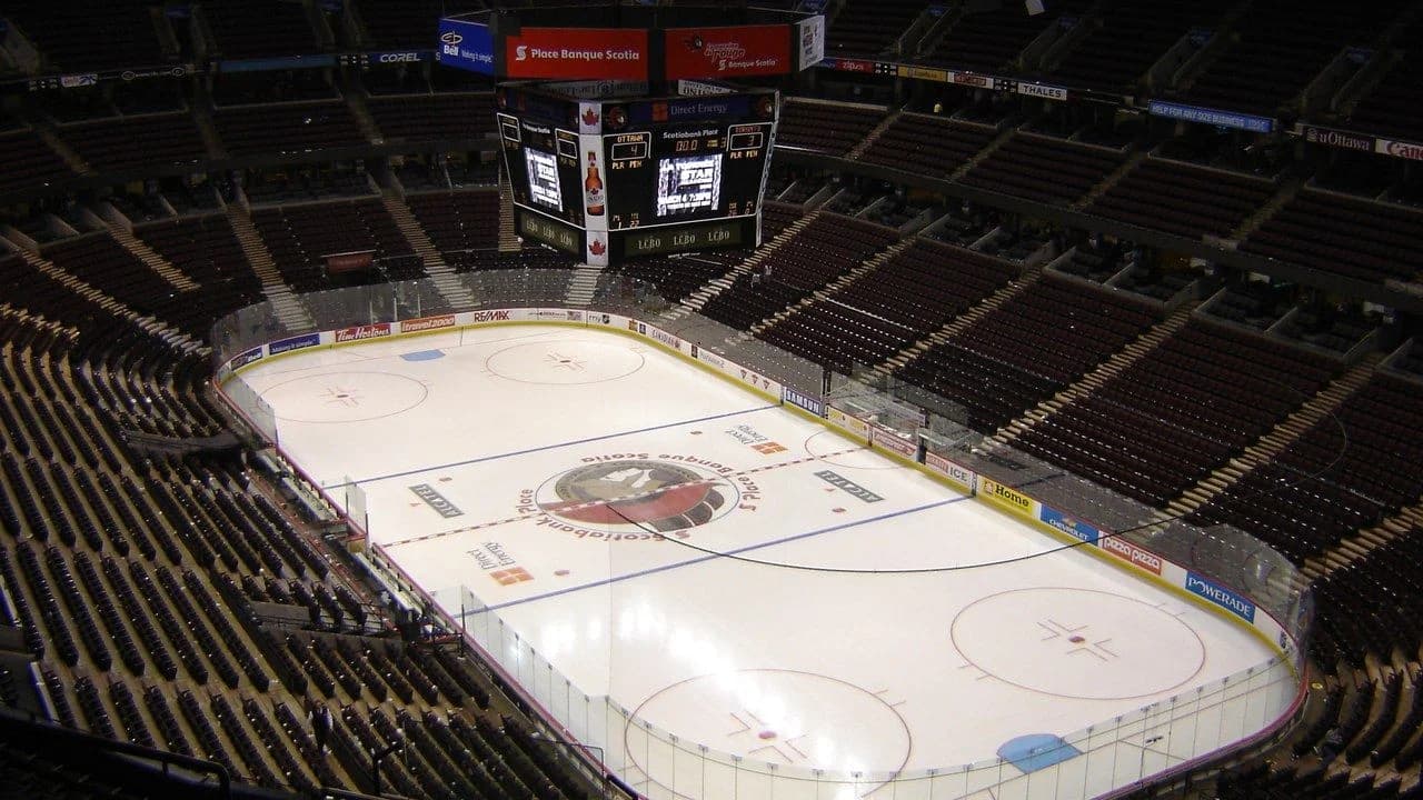 Empty interior of an Ottawa hockey arena: the ice rink, empty stands, and overhead scoreboard; no people visible.