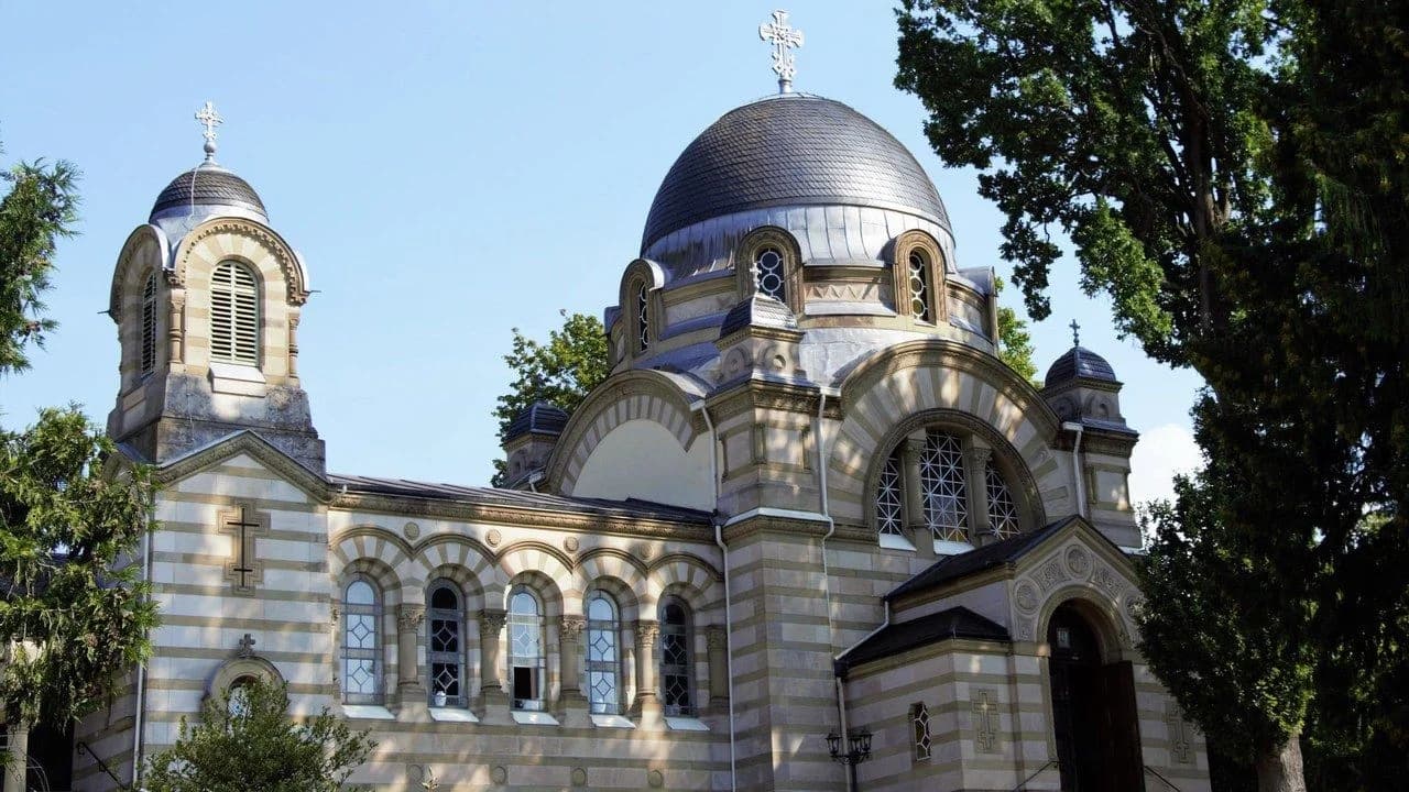 Exterior of a traditional domed Orthodox church with intricate architecture under a clear blue sky; no people visible