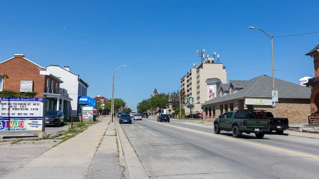 Daytime view looking west along King Street in downtown Bowmanville, Ontario, with storefronts on both sides of the main street; no people visible.