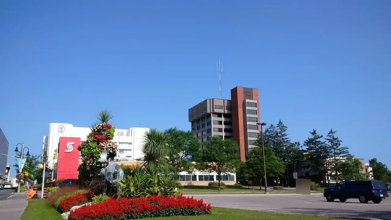 Oshawa City Hall tower behind a landscaped flower bed on a sunny day