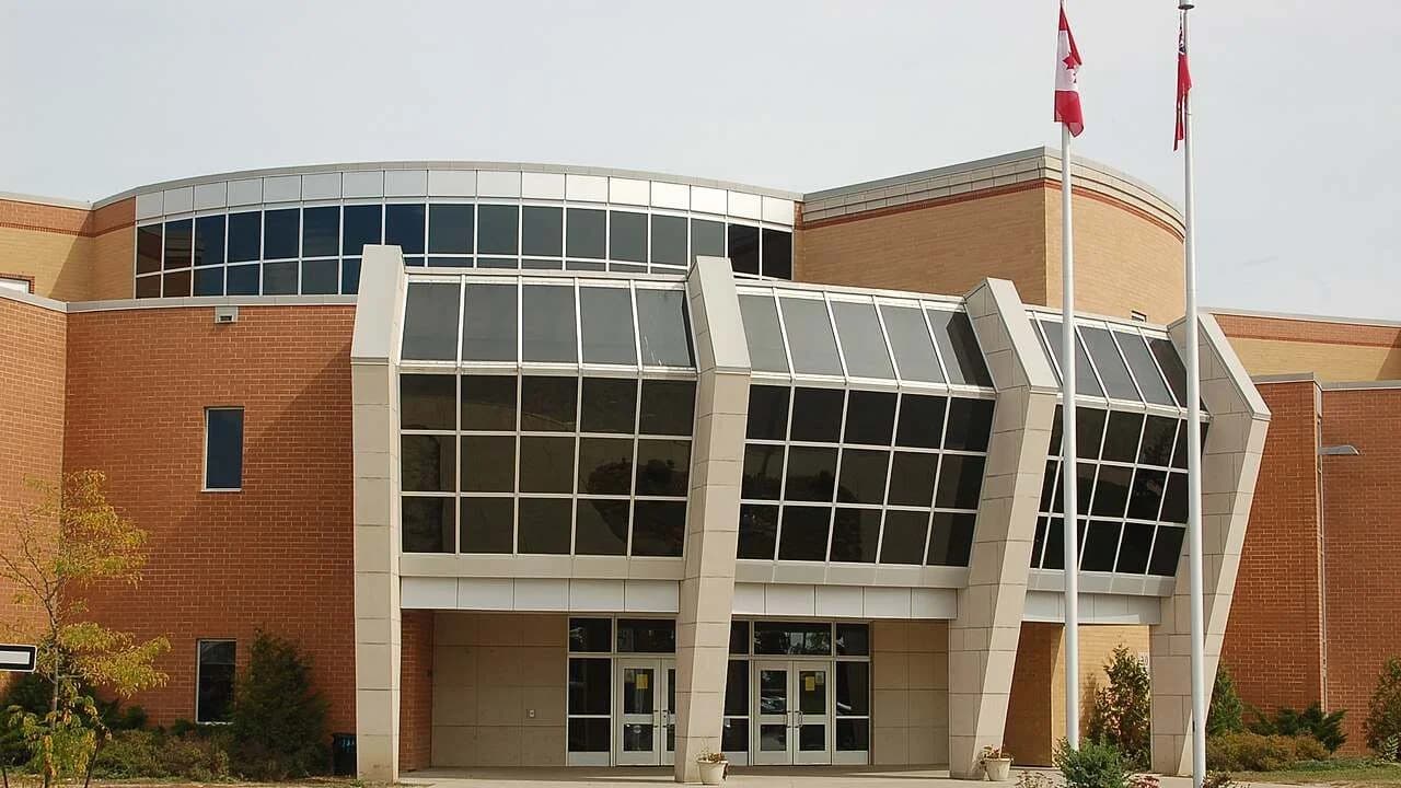 Entrance of All Saints Catholic Secondary School in Whitby, Ontario — a modern brick-and-glass school building; no people visible.