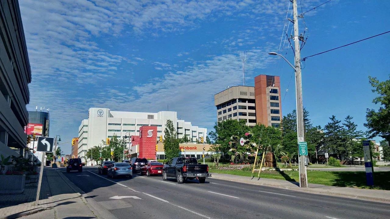 A daytime view east along King Street in Oshawa, Ontario, showing buildings, a Scotiabank branch, traffic lights and cars on the road; no pedestrians visible.